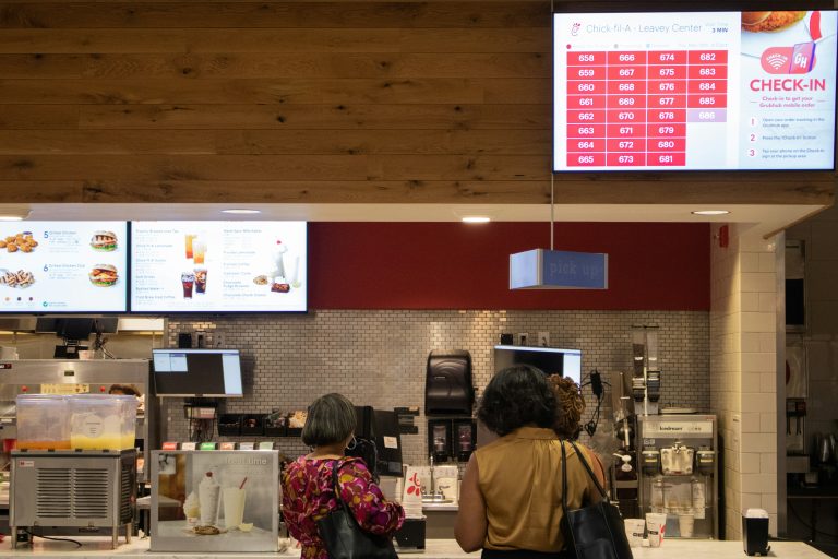 a couple of woman standing in front of self service kiosk