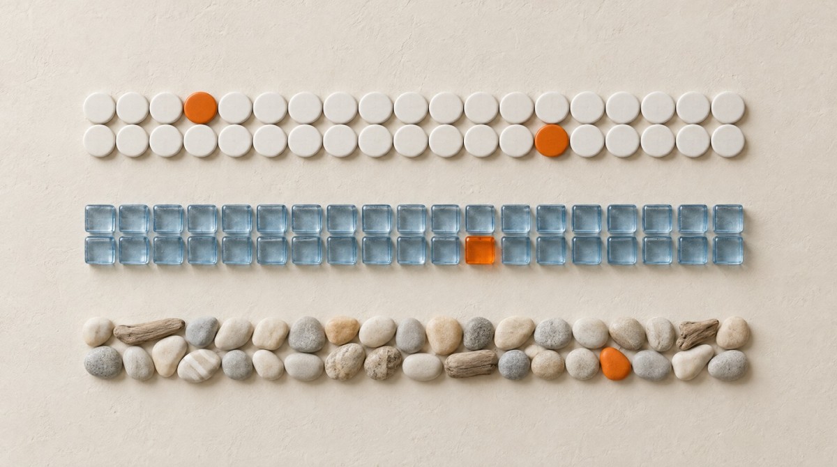 Trois rangées parallèles distinctes sur une surface claire : des carreaux ronds blancs, des cubes de verre bleu pâle et des galets avec des morceaux de bois flotté, chaque rangée avec une touche orange.